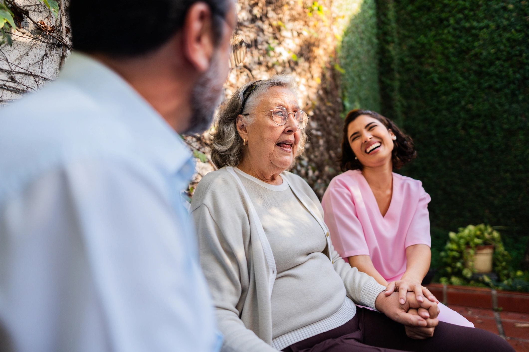 Family visiting and speaking with an elderly woman alongside a nurse